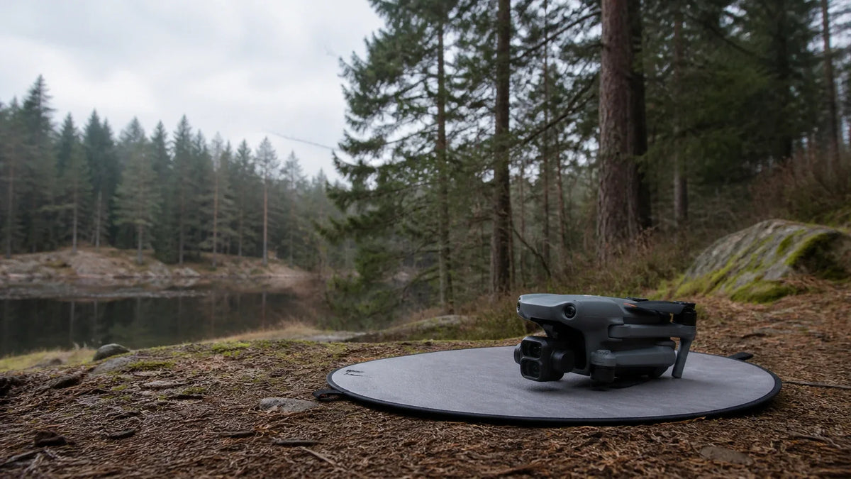 DJI Air 3 resting on a landing pad at a woodland trail edge before careful route planning
